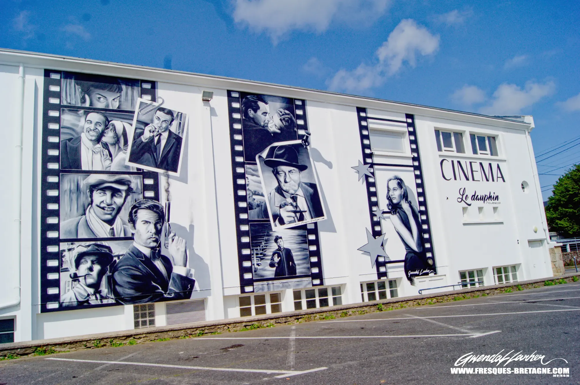 Street art noir et blanc : vue d'ensemble de la façade du cinéma Le Dauphin à Plouescat, trois grandes bandes de pellicule et portraits d'acteurs peints sur le mur, fresque murale monumentale d'un artiste graffeur
